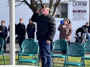 An elderly veteran salutes the flag.